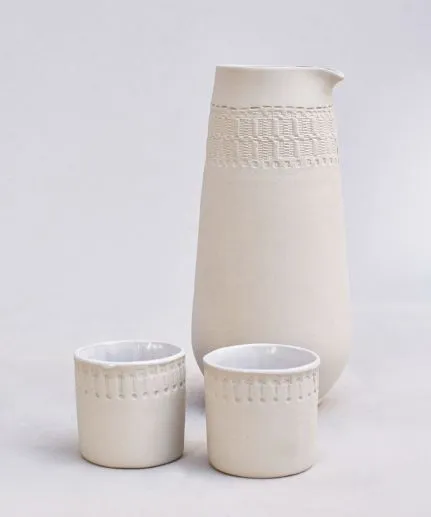 Handcrafted set of a cylinder pitcher and two small straight cups made of clay with embossed spathoto pattern