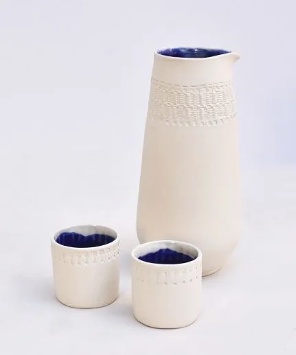 Handcrafted set of a cylinder pitcher and two small straight cups made of clay with embossed spathoto pattern